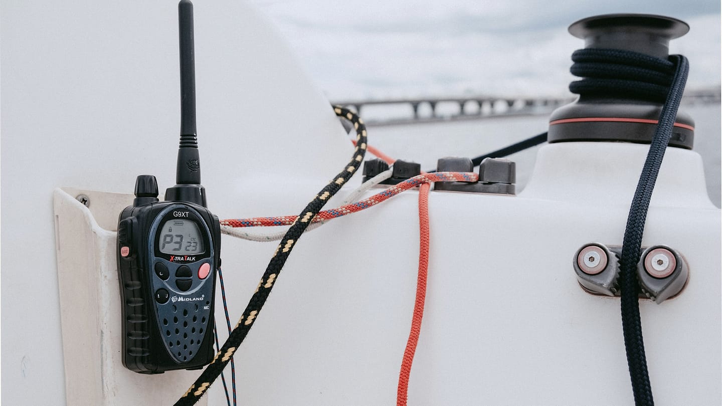 Handheld radio mounted beside running rigging in a sailboat cockpit