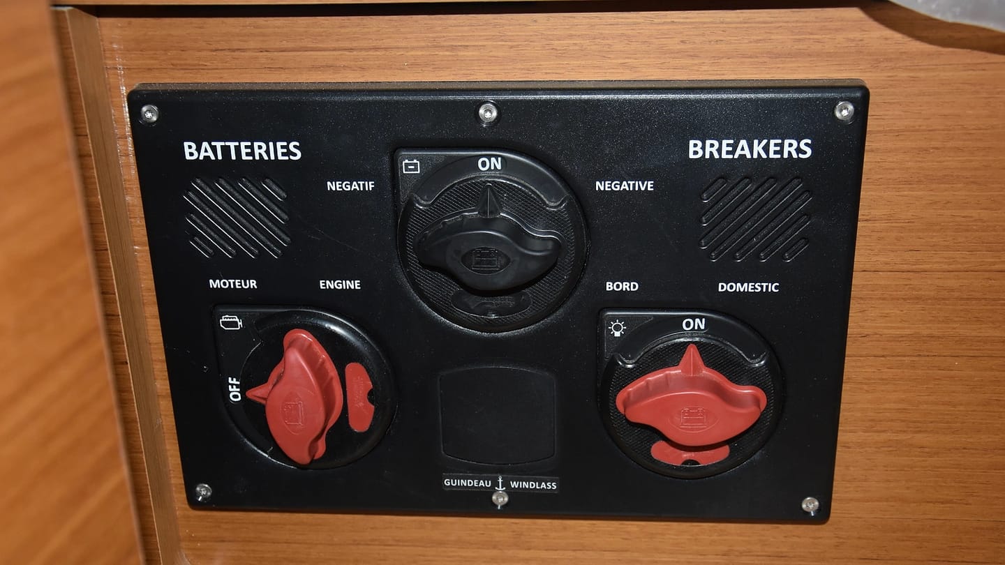 Battery switches mounted on a wooden panel inside a sailboat