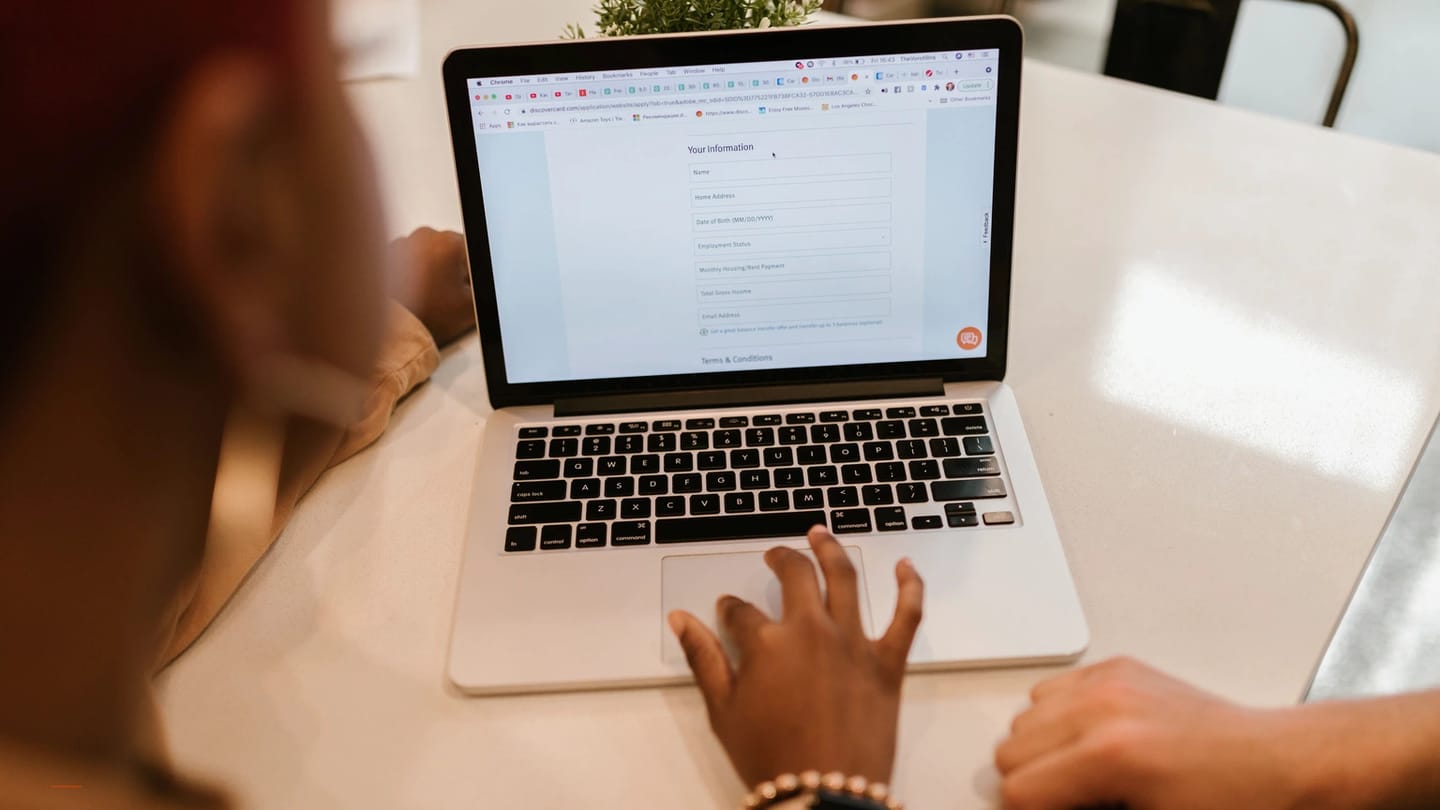 Laptop booking form open beside a pen and paper records