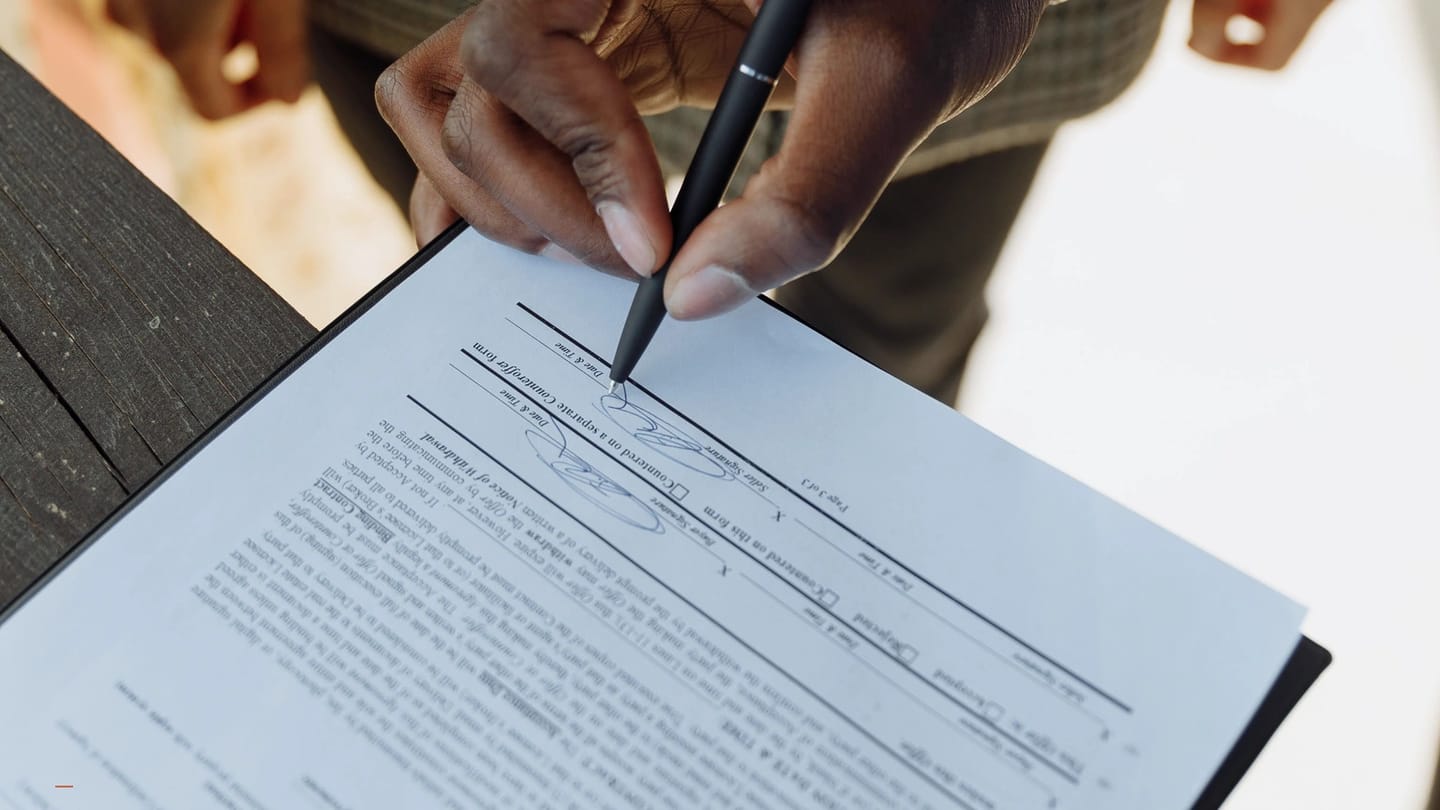 Agreement pages and signing hand shown close to the payment terms