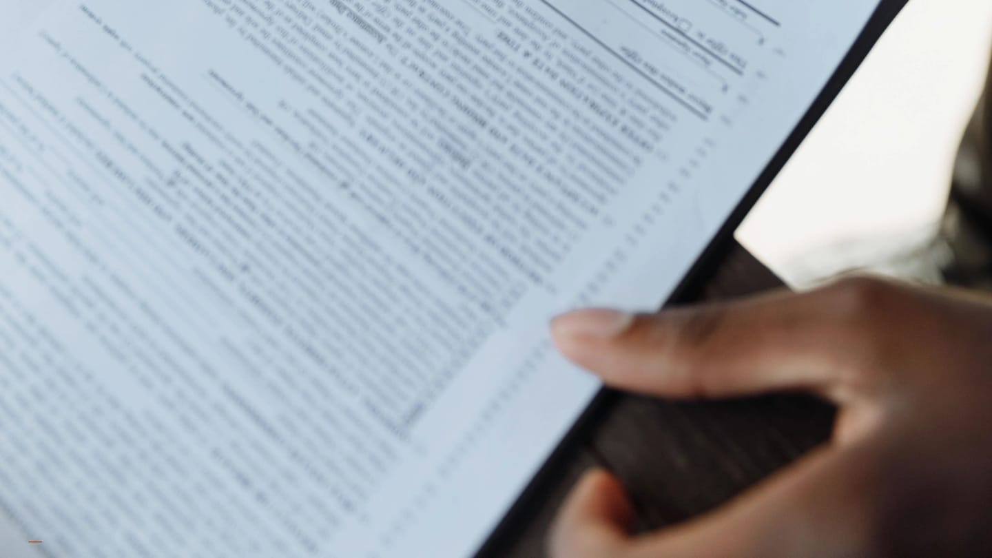 Pen, hand, and signature line on a printed contract