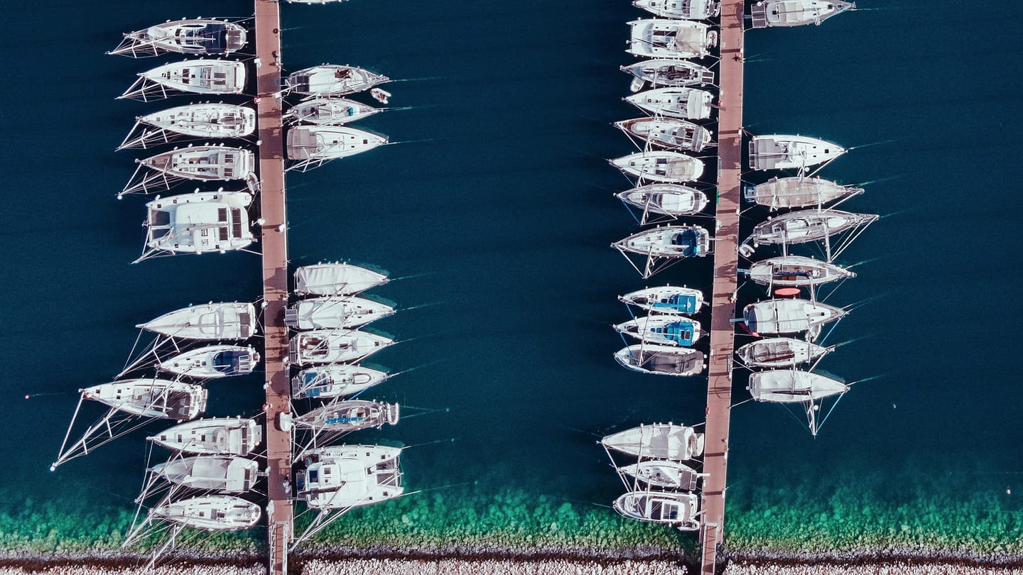 Charter sailboats lined up beside marina pontoons