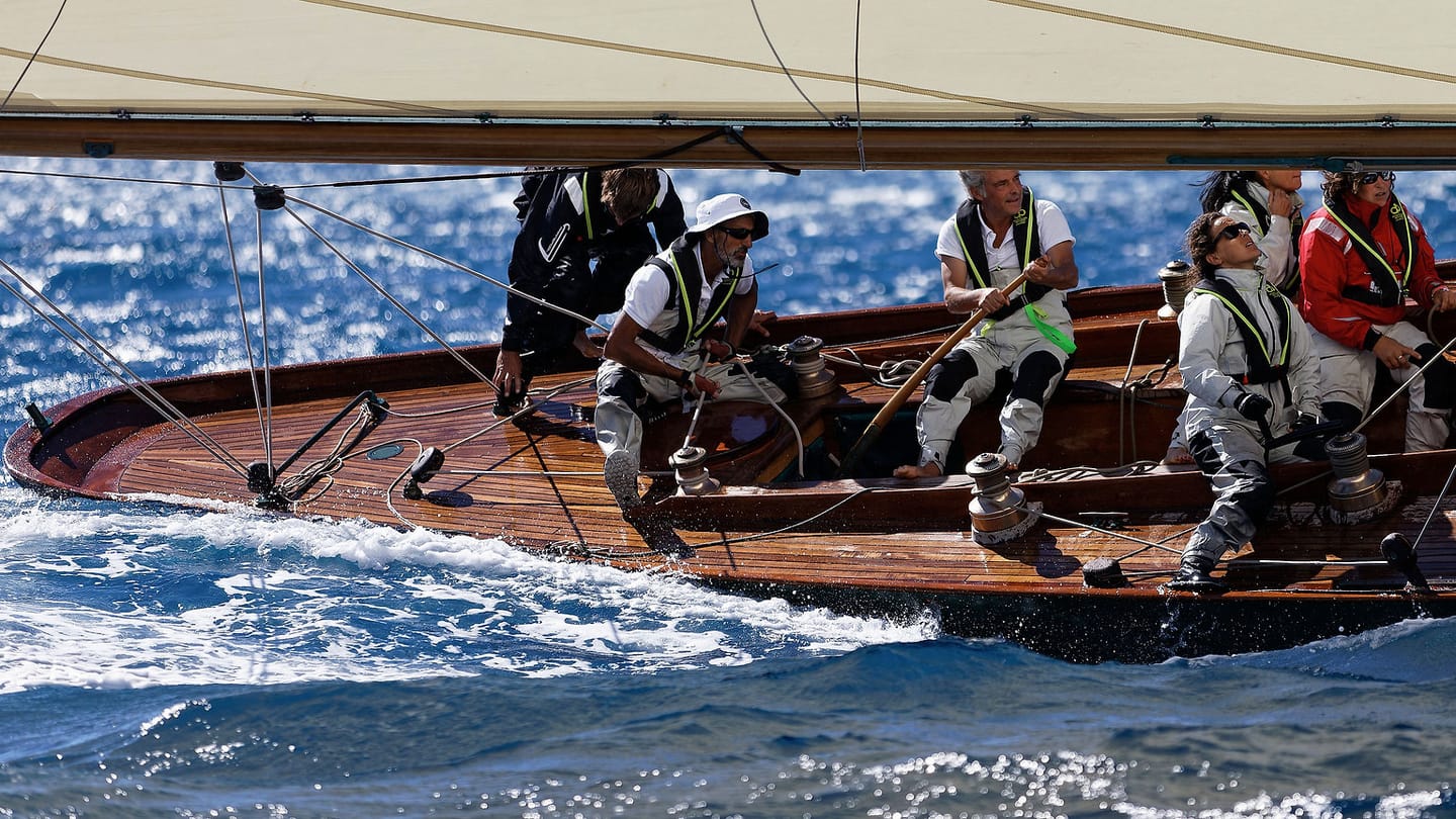Several sailors controlling lines aboard a heeled yacht