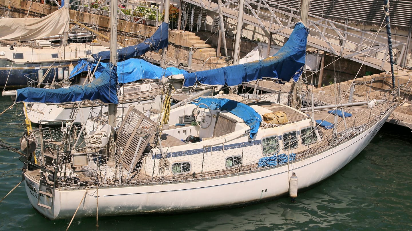 A sailboat enters a marina channel where the skipper must preserve a route back to deeper water.