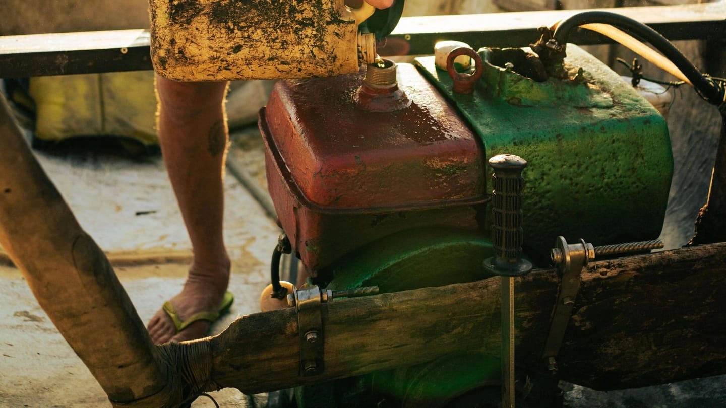 A person pours liquid into an engine in a small boat