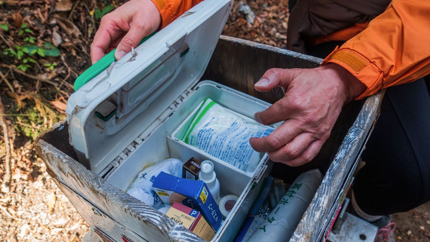 A hiker opening a real first-aid kit with both hands