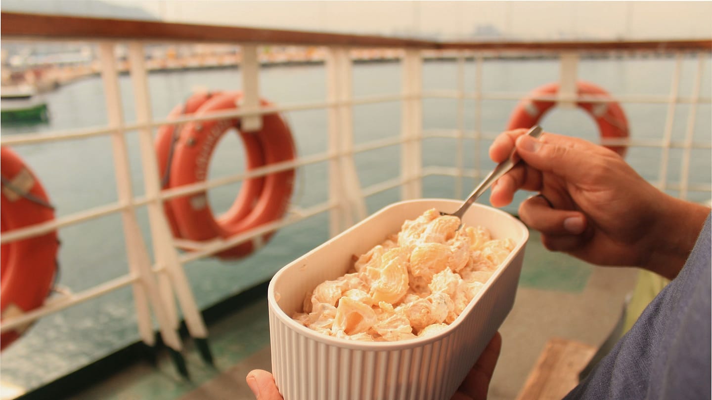 Person holding a simple meal on a boat deck