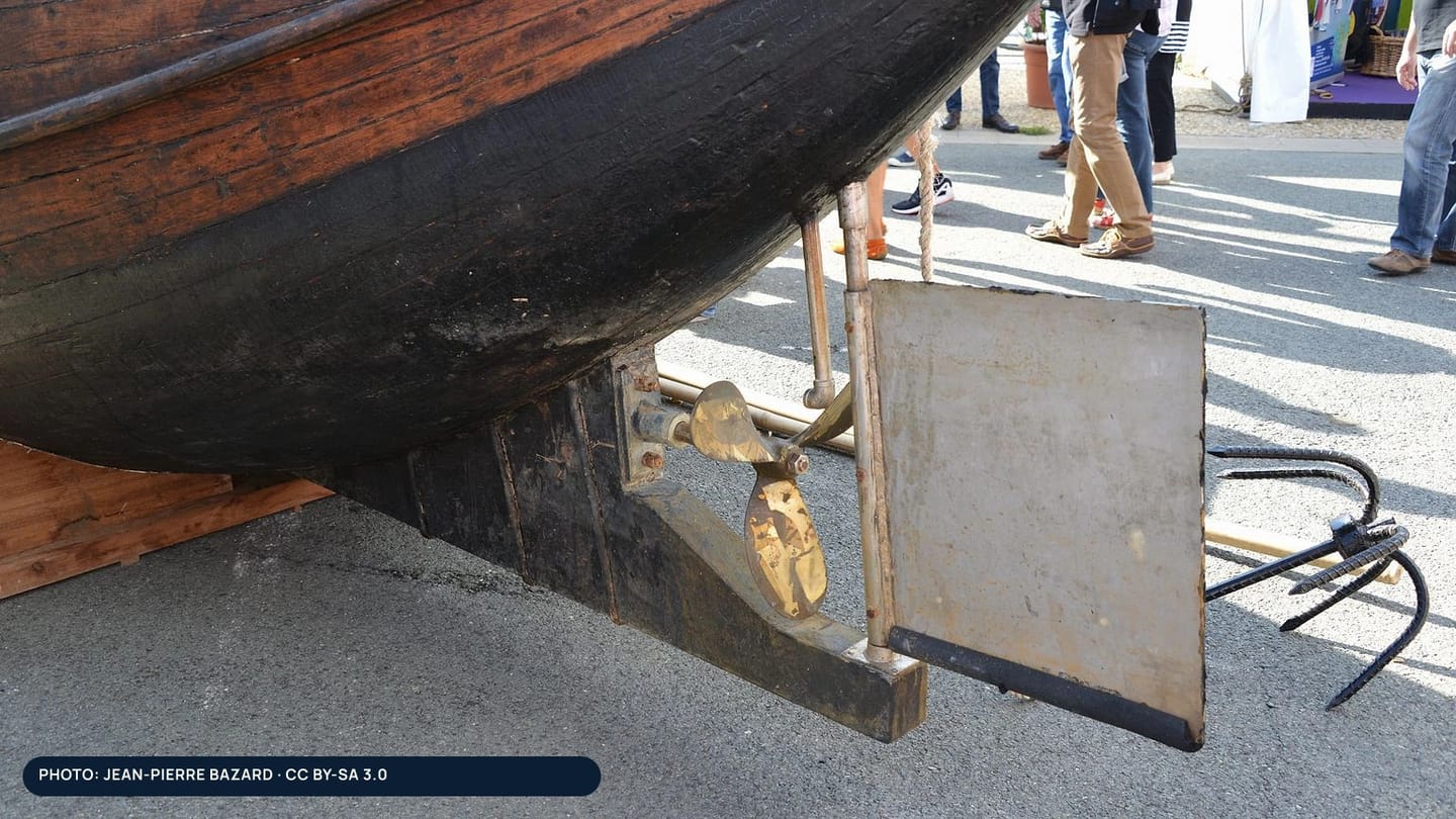 A sailboat rudder, stock, propeller, and lower bearing exposed ashore