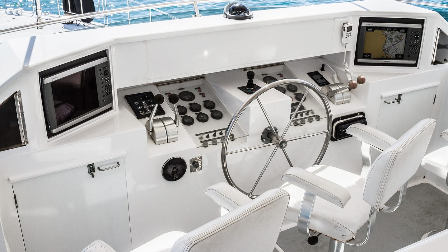 A boat helm console holds a wheel, gauges, switches, and electronic displays.