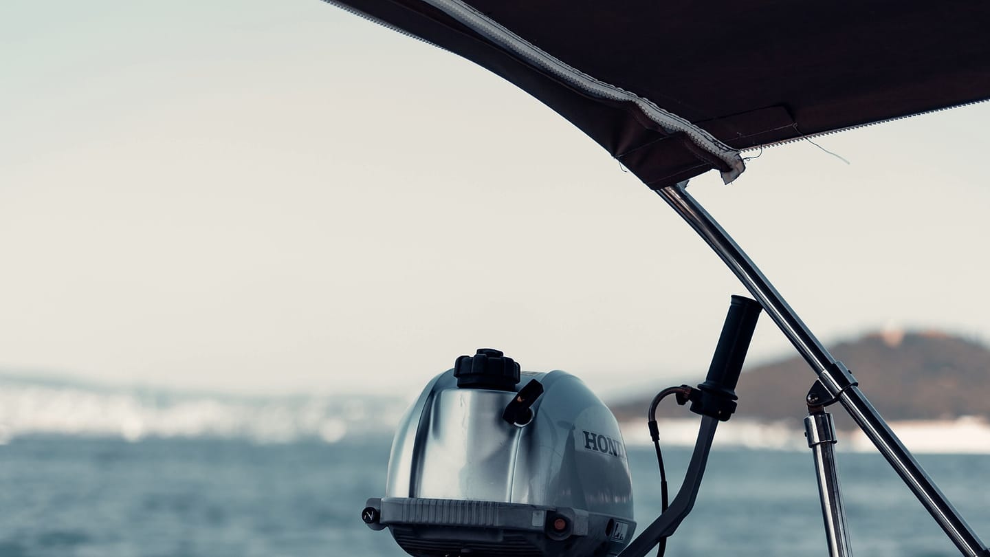 An outboard motor is mounted at the stern above blue water.