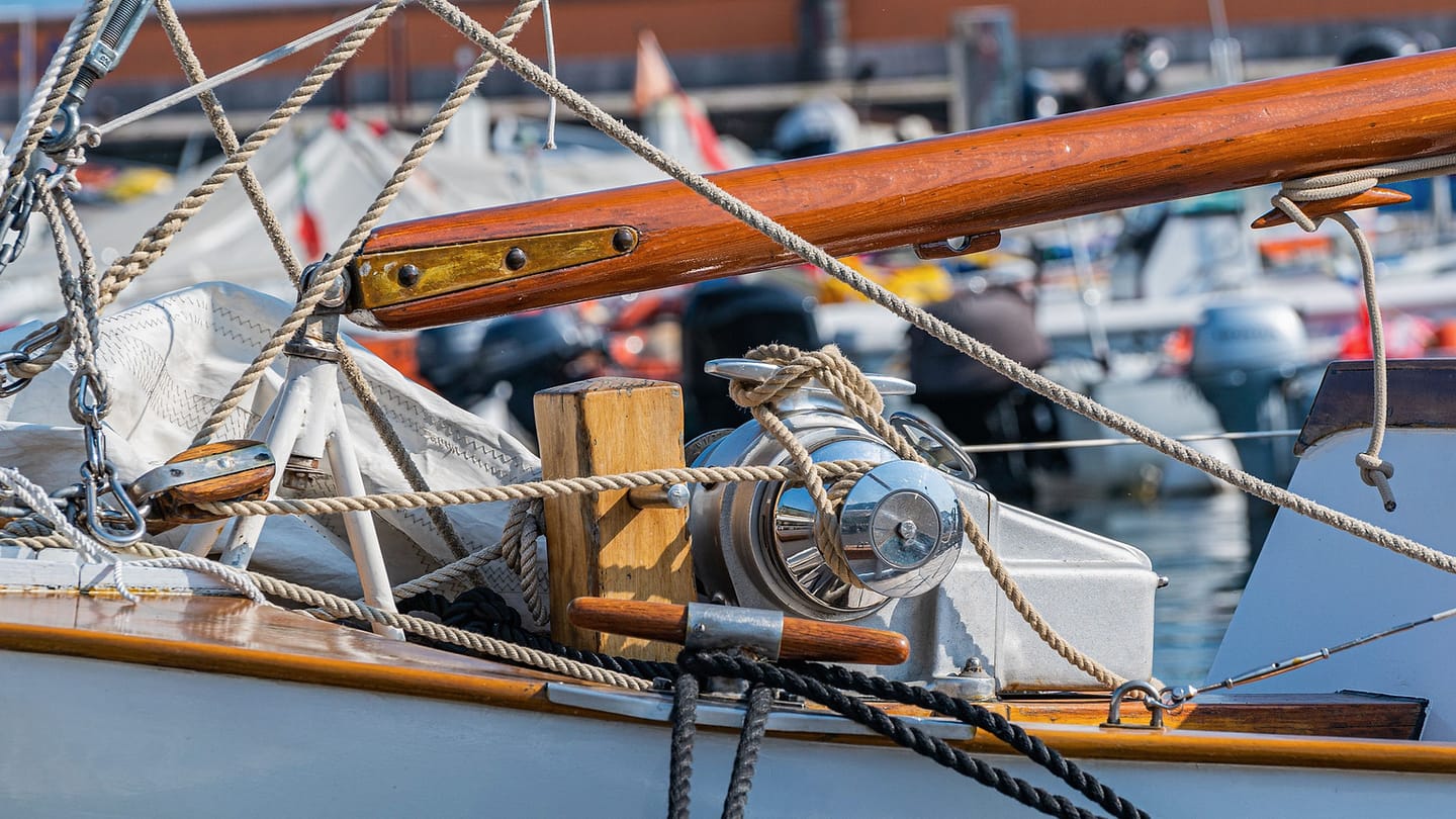 Several lines, fittings, and a pulley are visible on a sailboat deck.