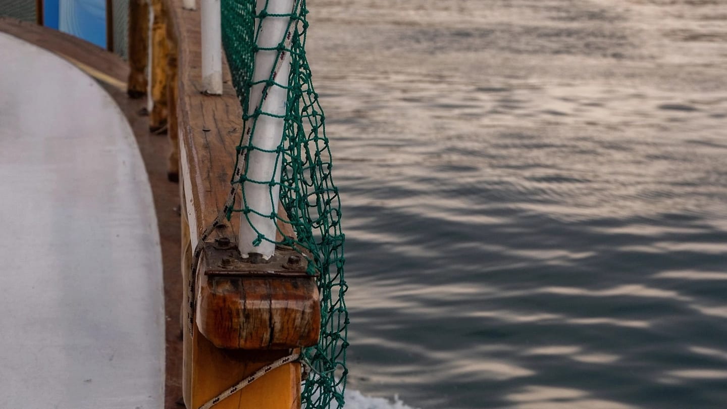 Wooden boat deck beside moving seawater