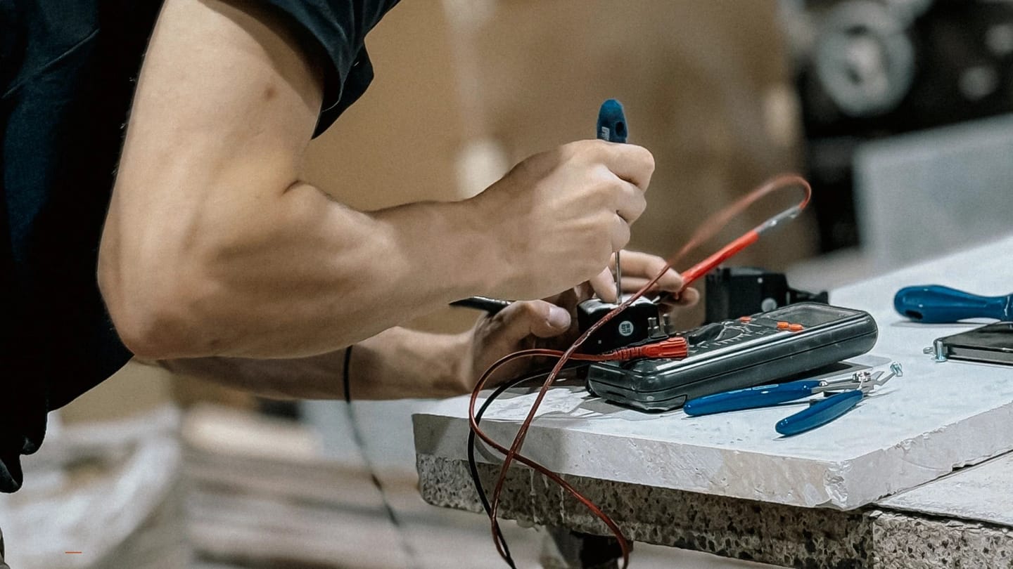 Technician holding meter probes against electrical equipment