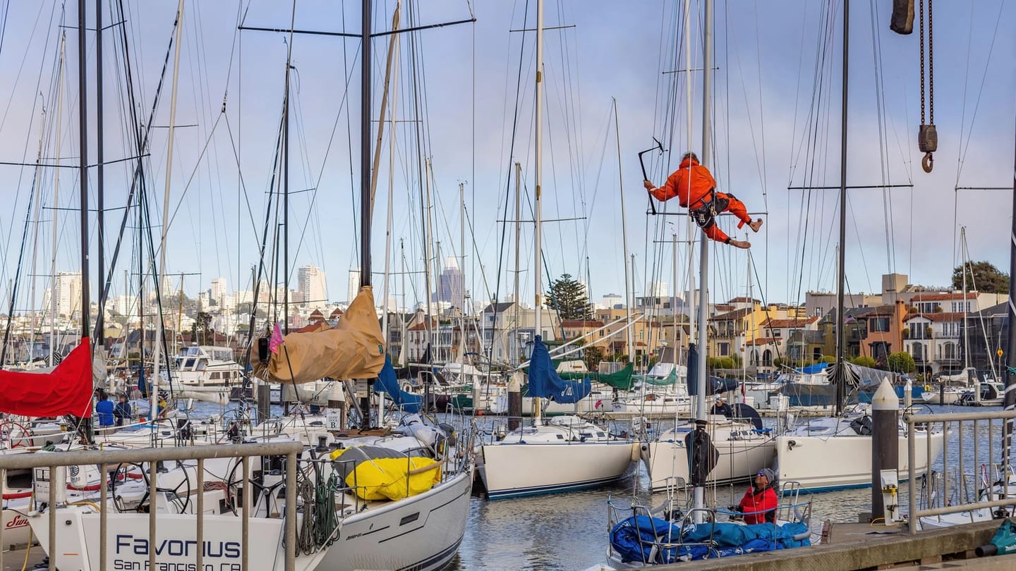 Sailboat maintenance worker with tools beside the hull