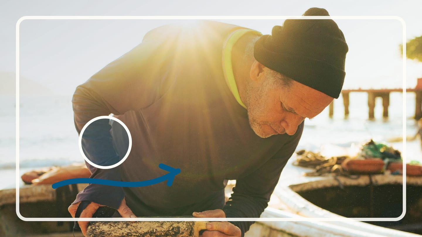 Man in a knit cap leaning over the edge of a boat in sunlight