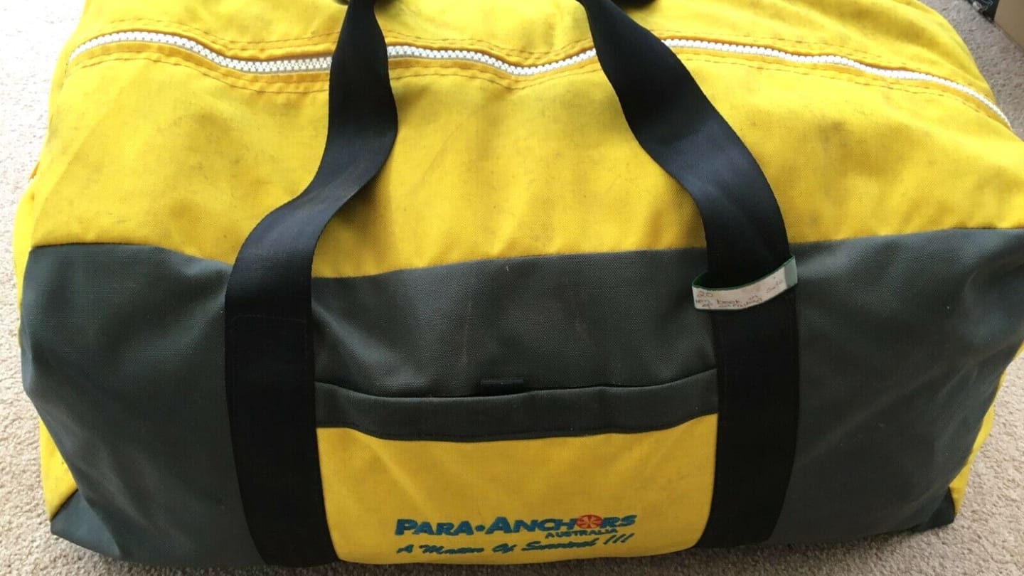A yellow and black parachute sea anchor bag with webbing handles and a white zipper