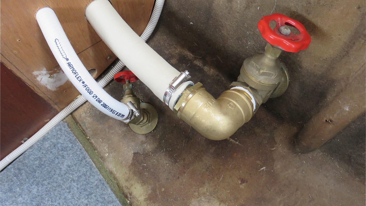 Two seacock valves and white hoses installed inside a pleasure craft