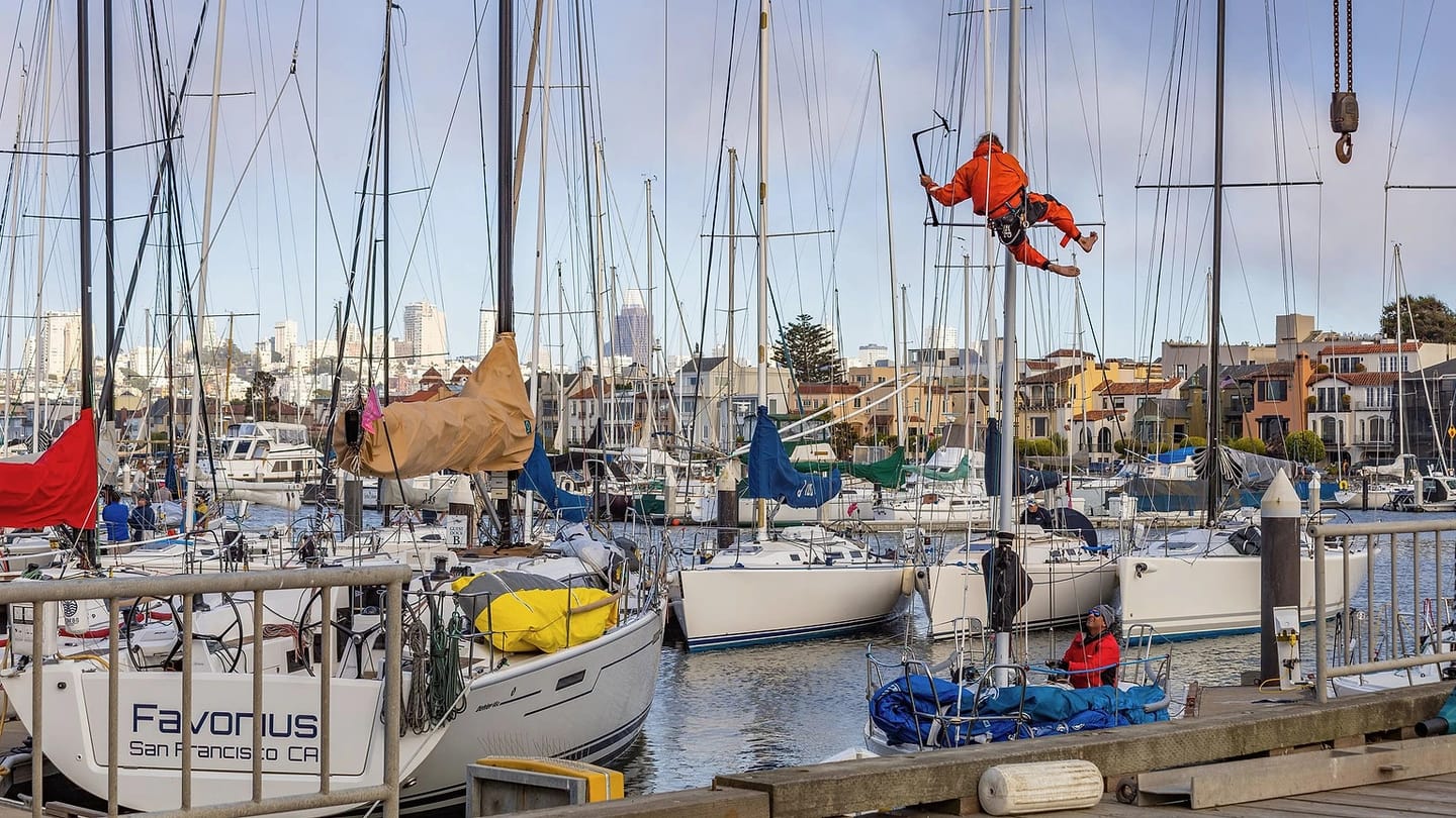 Person working on a sailboat beside a marina