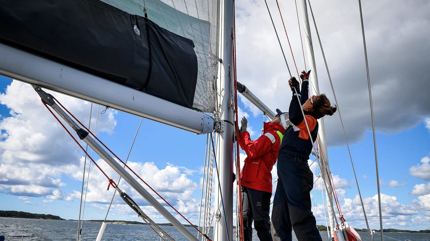Crew sailing beneath the rig of a yacht
