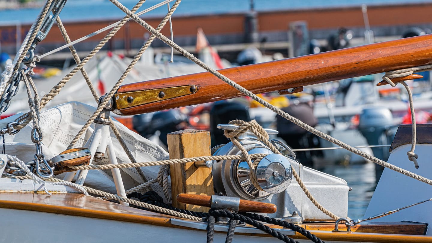 Coiled lines and metal rigging fittings lie across a sailboat deck.