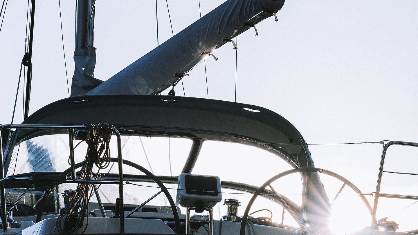 A white sailboat is moored beside a dock with calm water around its hull.