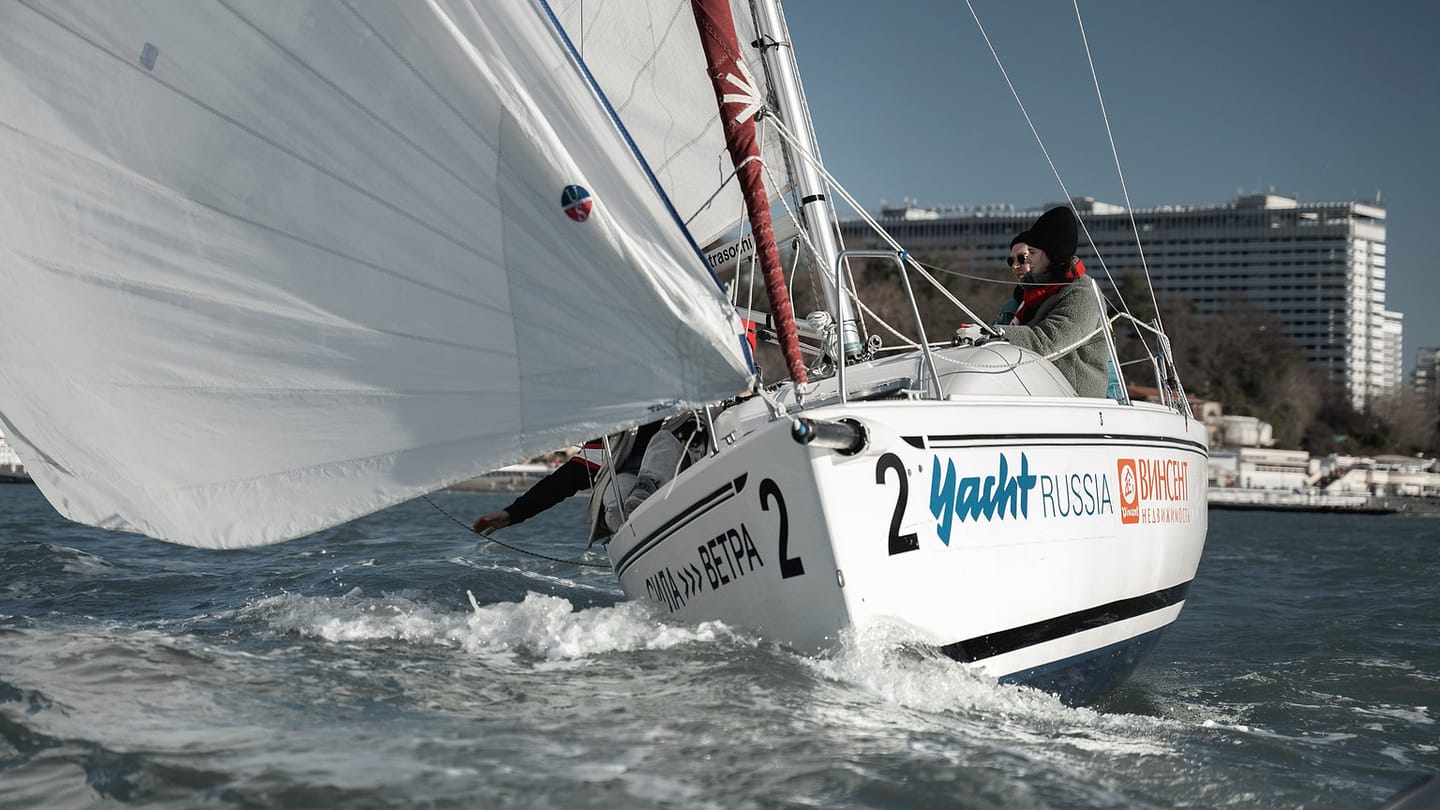 A heeled racing sailboat shows its hull pressed down to leeward under sail.