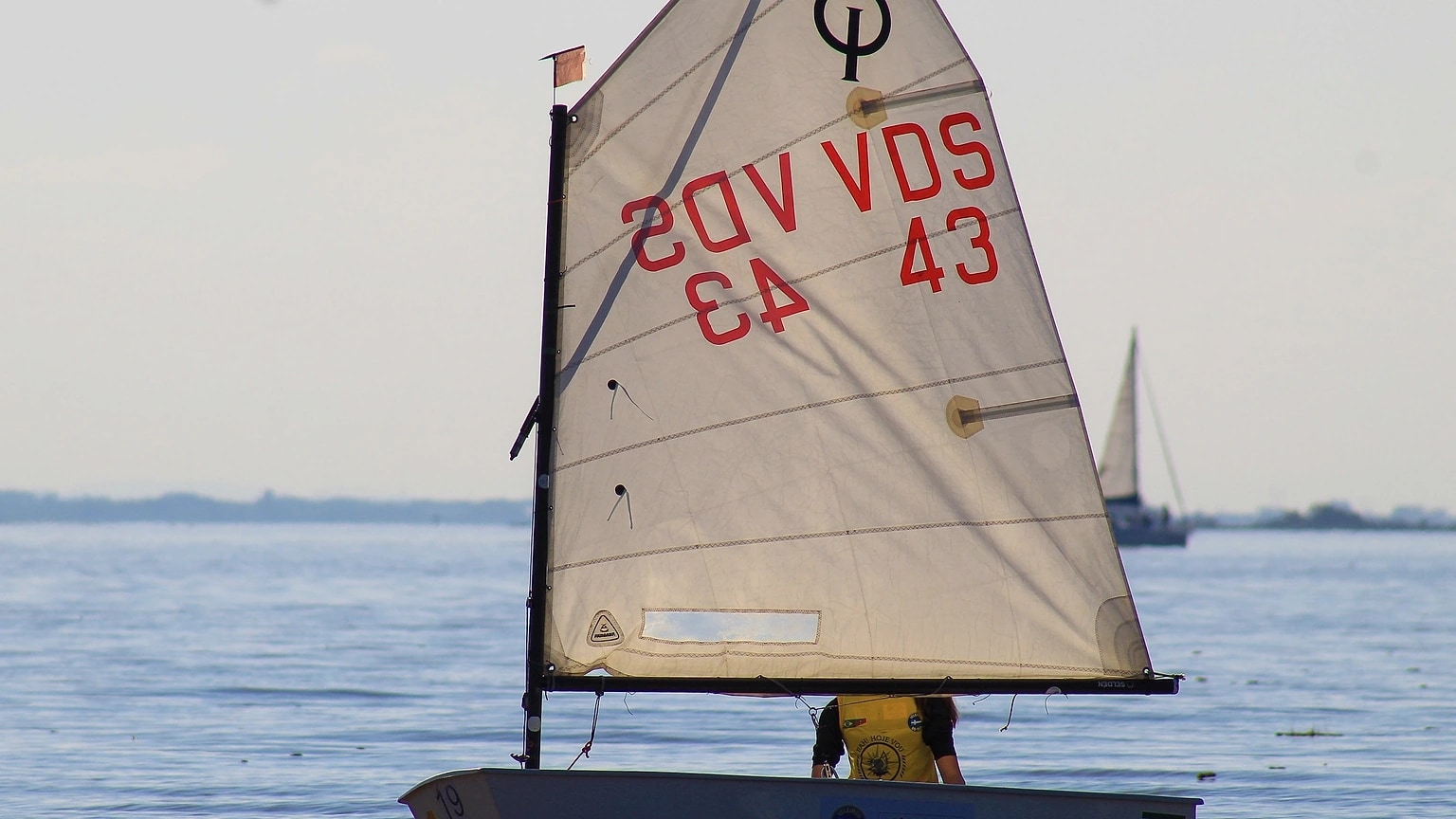 Sailboat with lightly filled sails on smooth water