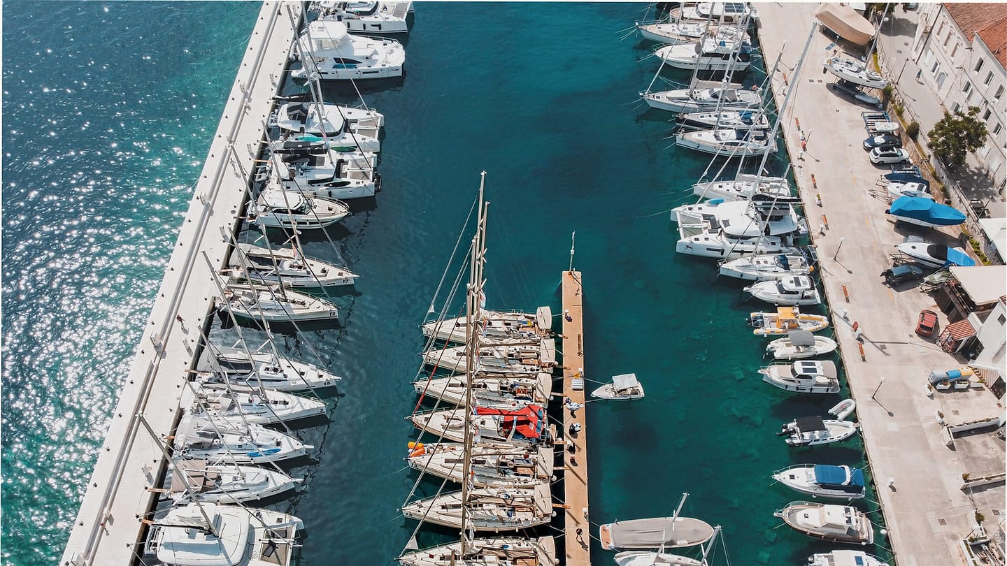 Sailboats gathered in a marina beside club facilities