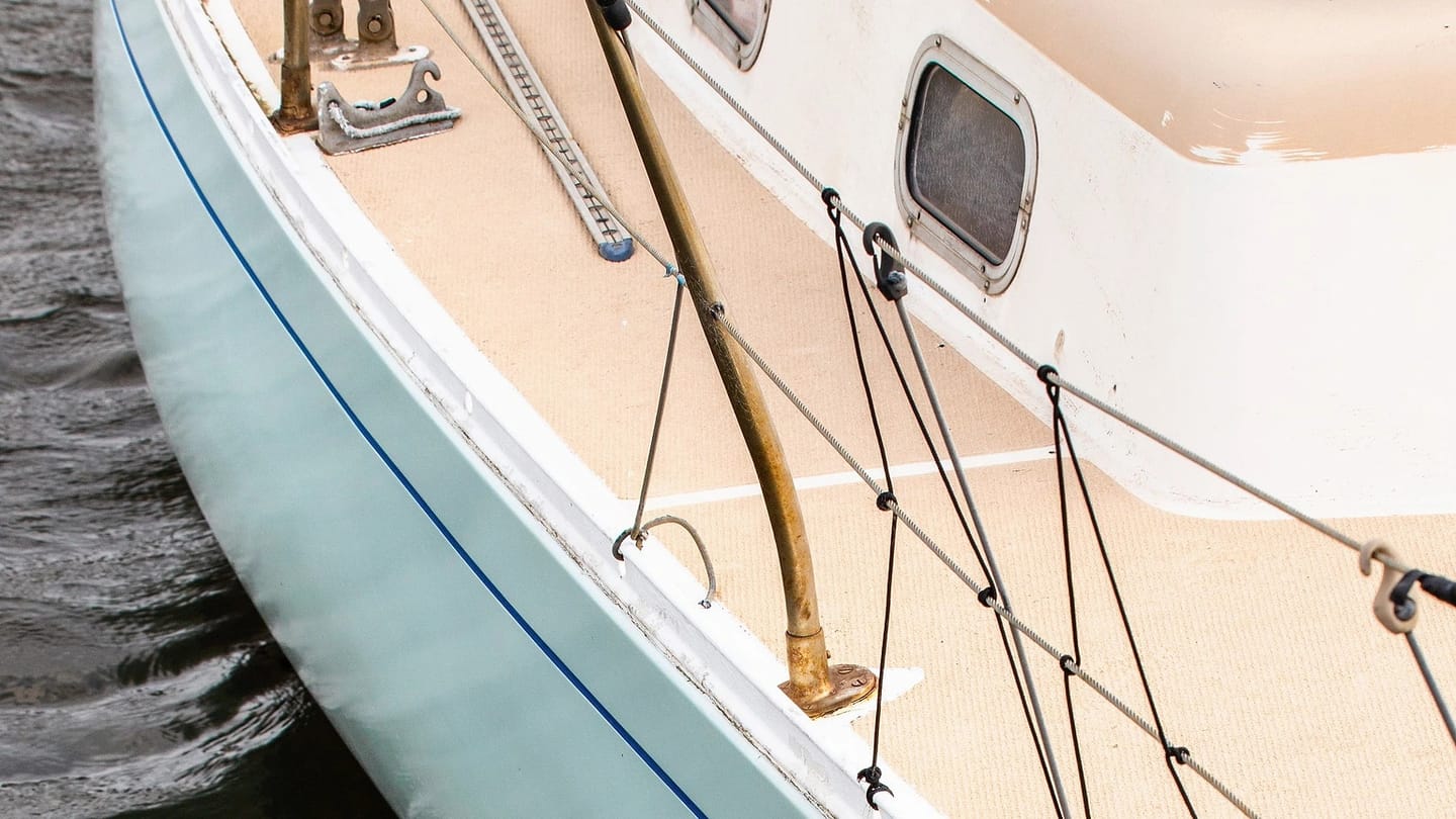 White sailboat hull reflected in calm water