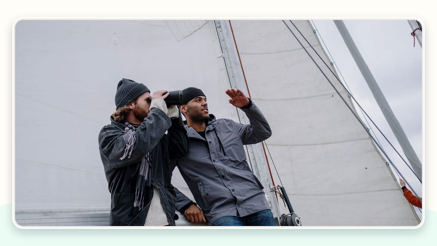 Two people talking beside a sail on a yacht deck